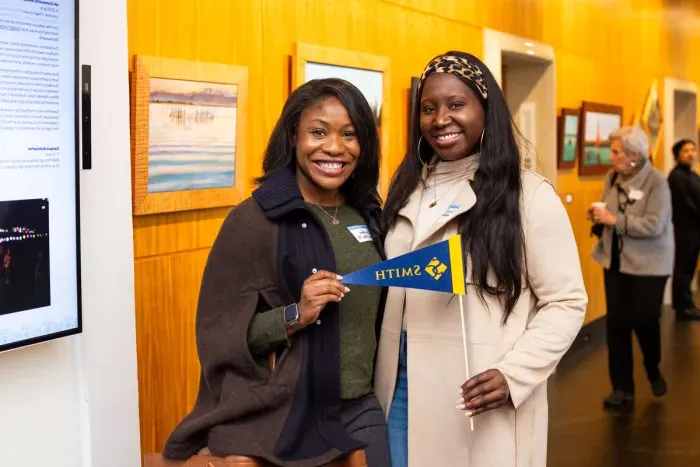 Two alums posing with a Smith College pennant. 